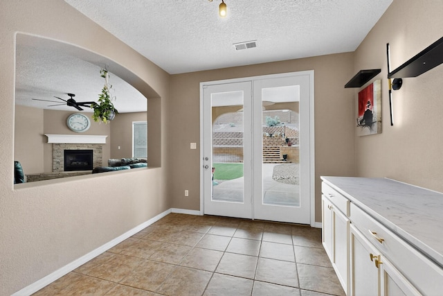 4420 Bentgrass Mdws NE, Rio Rancho, NM 87144 - doorway to outside with ceiling fan, a textured ceiling, a stone fireplace, light tile patterned floors, and arched walkways