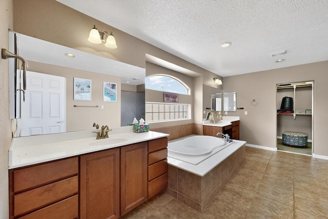 4420 Bentgrass Mdws NE, Rio Rancho, NM 87144 - bathroom featuring a garden tub, two vanities, a textured ceiling, tile patterned flooring, and recessed lighting