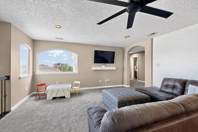 4420 Bentgrass Mdws NE, Rio Rancho, NM 87144 - carpeted living room with arched walkways, a ceiling fan, and a textured ceiling