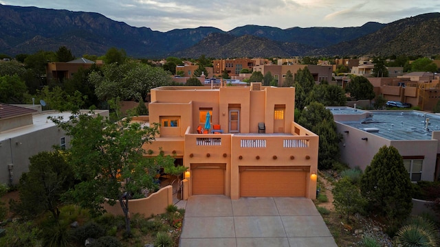 5808 Mariola Pl NE, Albuquerque, NM 87111 - pueblo-style home featuring concrete driveway, a garage, a mountain view, stucco siding, and a residential view