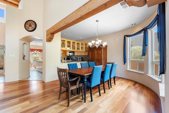 5808 Mariola Pl NE, Albuquerque, NM 87111 - dining space with a chandelier, arched walkways, light wood-style floors, and beam ceiling