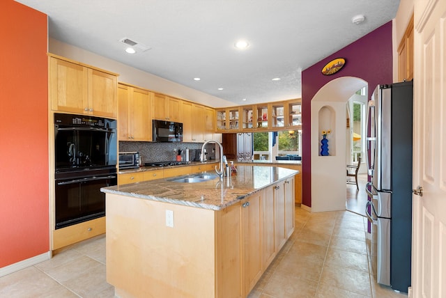 5808 Mariola Pl NE, Albuquerque, NM 87111 - kitchen featuring black appliances, arched walkways, a center island with sink, light stone counters, and tasteful backsplash