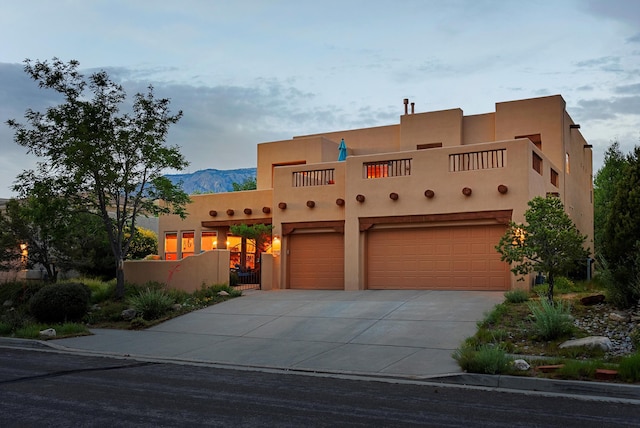 5808 Mariola Pl NE, Albuquerque, NM 87111 - pueblo-style home with an attached garage, concrete driveway, stucco siding, and a mountain view