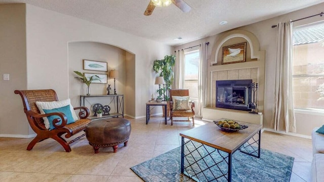 851 Vista Patron Dr, Bernalillo, NM 87004 - tiled living room featuring a textured ceiling, ceiling fan, arched walkways, and a tile fireplace