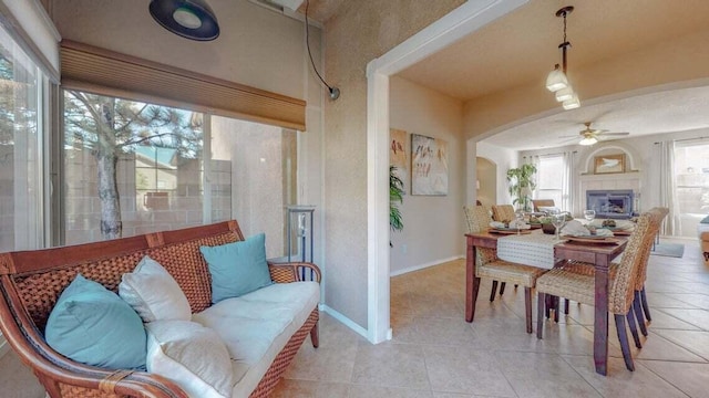 851 Vista Patron Dr, Bernalillo, NM 87004 - dining room featuring ceiling fan, arched walkways, light tile patterned floors, and a fireplace