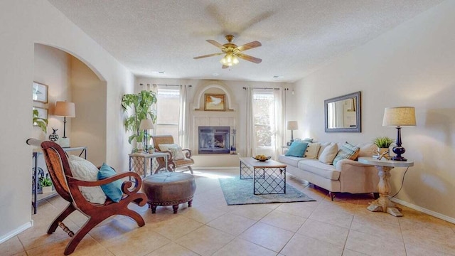 851 Vista Patron Dr, Bernalillo, NM 87004 - living area with ceiling fan, arched walkways, a textured ceiling, light tile patterned floors, and a tiled fireplace