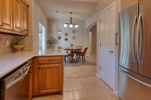 851 Vista Patron Dr, Bernalillo, NM 87004 - kitchen with appliances with stainless steel finishes, backsplash, arched walkways, light tile patterned floors, and light countertops