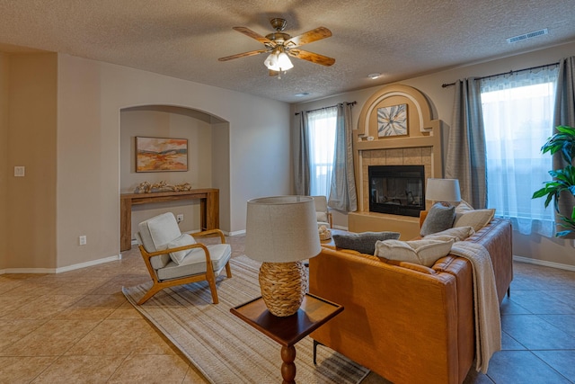 851 Vista Patron Dr, Bernalillo, NM 87004 - living room with a fireplace, a textured ceiling, a ceiling fan, light tile patterned floors, and arched walkways