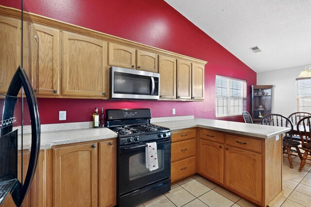 2062 Valley View Dr SW, Los Lunas, NM 87031 - kitchen with stainless steel microwave, black gas stove, vaulted ceiling, freestanding refrigerator, and light countertops