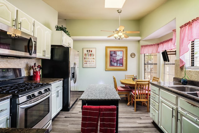 5131 Gaviota NW, Albuquerque, NM 87120 - kitchen featuring appliances with stainless steel finishes, dark countertops, backsplash, and wood finished floors