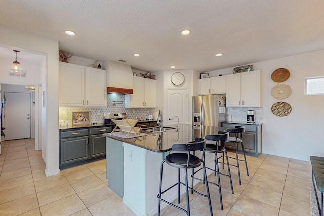 5716 Strand Loop SE, Albuquerque, NM 87106 - kitchen with stainless steel appliances, light tile patterned floors, white cabinets, tasteful backsplash, and a kitchen bar