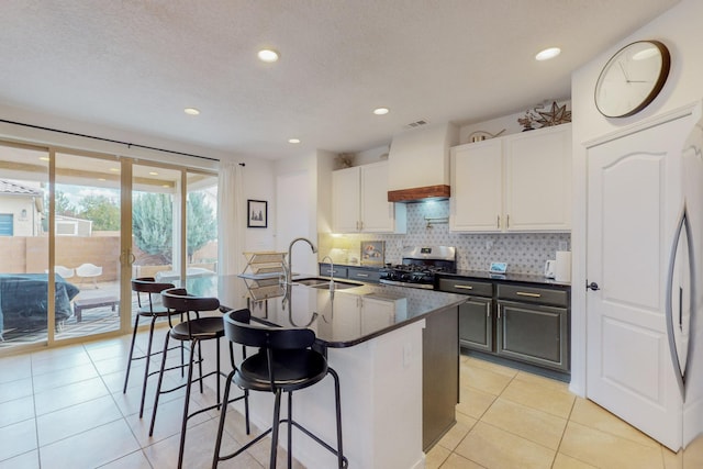 5716 Strand Loop SE, Albuquerque, NM 87106 - kitchen featuring stainless steel range with gas cooktop, a kitchen breakfast bar, backsplash, white cabinets, and a center island with sink