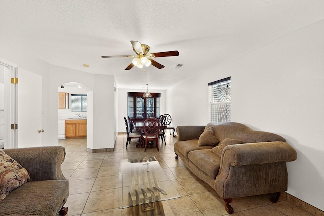 9900 Ladder Ranch Ln SW, Albuquerque, NM 87121 - living area with arched walkways, a ceiling fan, light tile patterned floors, and a textured ceiling