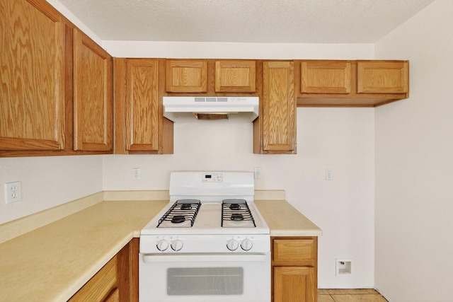 9900 Ladder Ranch Ln SW, Albuquerque, NM 87121 - kitchen featuring white gas stove, under cabinet range hood, light countertops, and brown cabinets