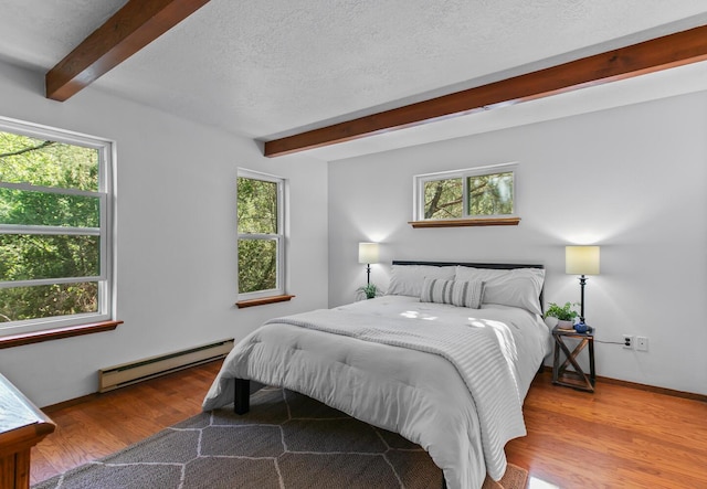 113 Sandia Crest Rd, Sandia Park, NM 87047 - bedroom with baseboard heating, beam ceiling, multiple windows, wood finished floors, and a textured ceiling