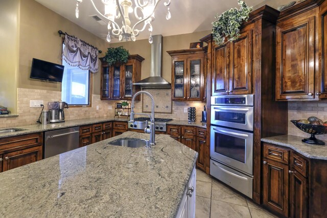9604 Big Sage Dr NW, Albuquerque, NM 87114 - kitchen with appliances with stainless steel finishes, wall chimney exhaust hood, a warming drawer, backsplash, and light stone countertops