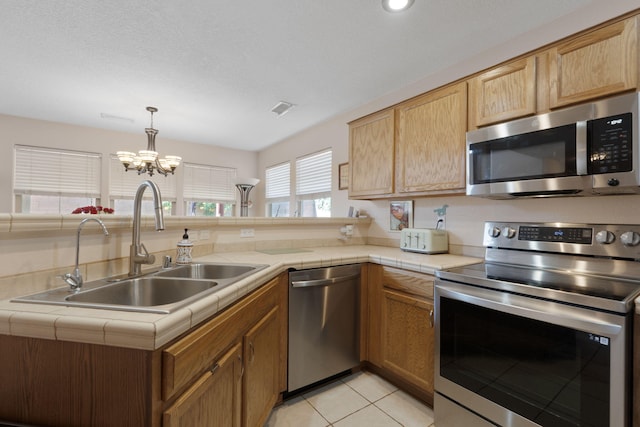 10027 Vista Cantera Ln NW, Albuquerque, NM 87114 - kitchen with appliances with stainless steel finishes, tile countertops, a chandelier, a peninsula, and light tile patterned floors