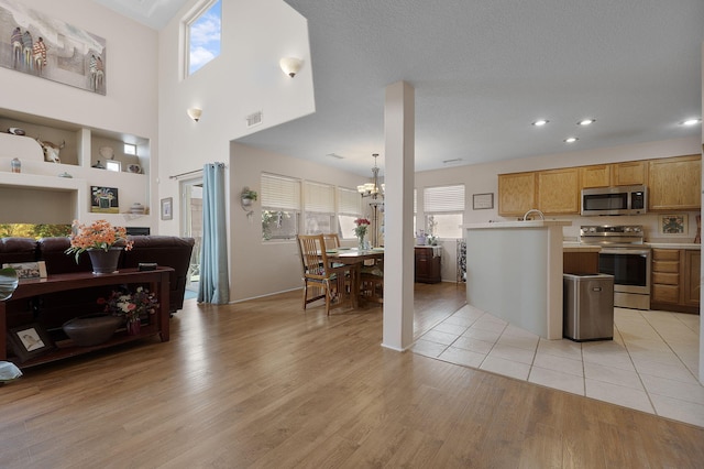 10027 Vista Cantera Ln NW, Albuquerque, NM 87114 - kitchen with stainless steel appliances, light countertops, open floor plan, a chandelier, and light wood finished floors