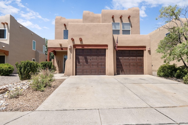 10027 Vista Cantera Ln NW, Albuquerque, NM 87114 - pueblo revival-style home with concrete driveway, stucco siding, and a garage