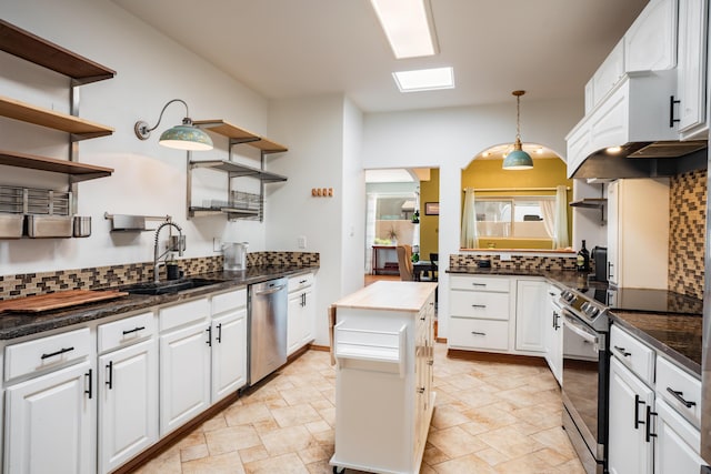 5 Ocotillo Way, Placitas, NM 87043 - kitchen featuring appliances with stainless steel finishes, open shelves, decorative backsplash, and stone tile flooring
