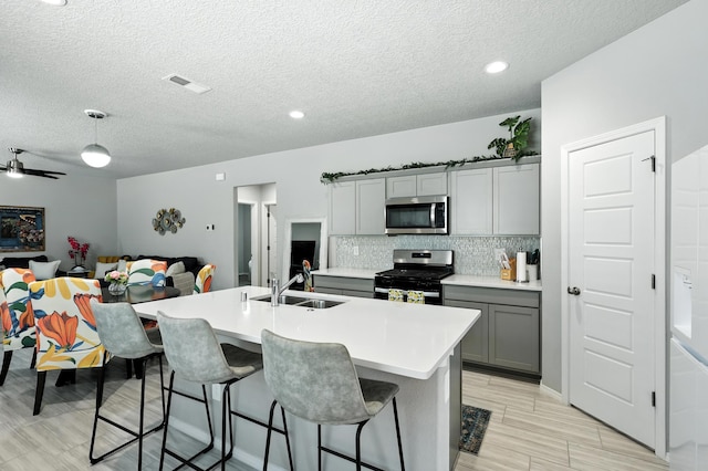 583 Turmalina Dr SE, Rio Rancho, NM 87124 - kitchen featuring appliances with stainless steel finishes, gray cabinets, decorative backsplash, light countertops, and a textured ceiling