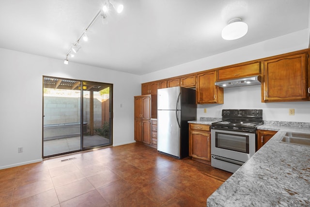 504 Ortiz Dr NE, Albuquerque, NM 87108 - kitchen featuring appliances with stainless steel finishes, under cabinet range hood, brown cabinets, dark tile patterned flooring, and track lighting