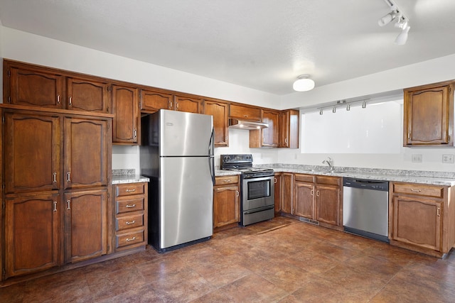 504 Ortiz Dr NE, Albuquerque, NM 87108 - kitchen featuring stainless steel appliances, under cabinet range hood, rail lighting, light countertops, and brown cabinets
