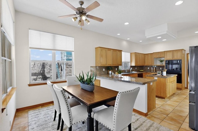 13100 Desert Moon Pl NE, Albuquerque, NM 87111 - kitchen with black appliances, decorative backsplash, a kitchen island, light tile patterned flooring, and ceiling fan