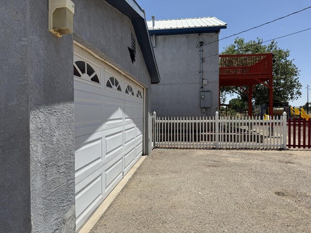 4 Los Chavez Park Rd, Belen, NM 87002 - view of side of home featuring a garage, stucco siding, and a metal roof