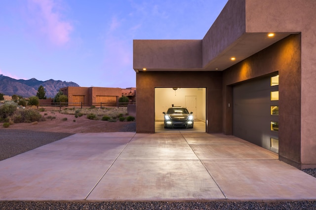 24 Norte Trl, Placitas, NM 87043 - property exterior at dusk featuring a mountain view, stucco siding, and concrete driveway