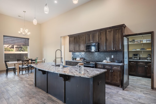 24 Norte Trl, Placitas, NM 87043 - kitchen featuring appliances with stainless steel finishes, a chandelier, light stone countertops, light wood finished floors, and a high ceiling
