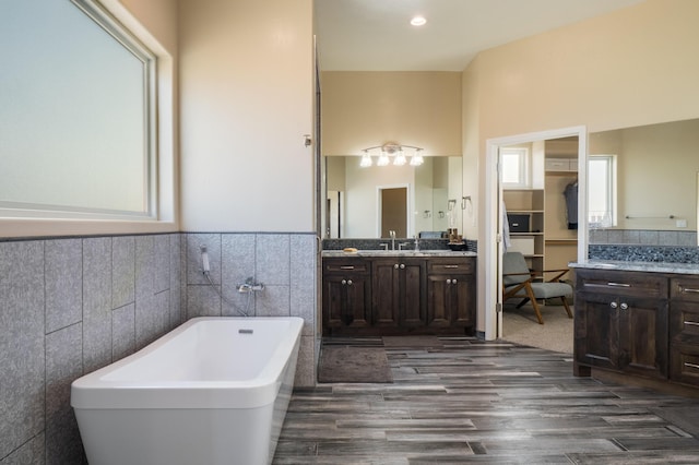 24 Norte Trl, Placitas, NM 87043 - full bathroom with a freestanding bath, tile walls, wood finished floors, vanity, and wainscoting