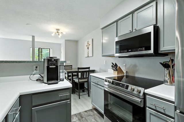 4801 Irving Blvd NW Unit 304, Albuquerque, NM 87114 - kitchen with stainless steel appliances, gray cabinetry, light countertops, and a textured ceiling