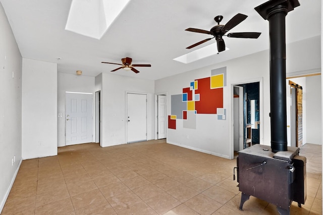 228 18th St SW, Rio Rancho, NM 87124 - empty room featuring a skylight, ceiling fan, light tile patterned floors, and a wood stove