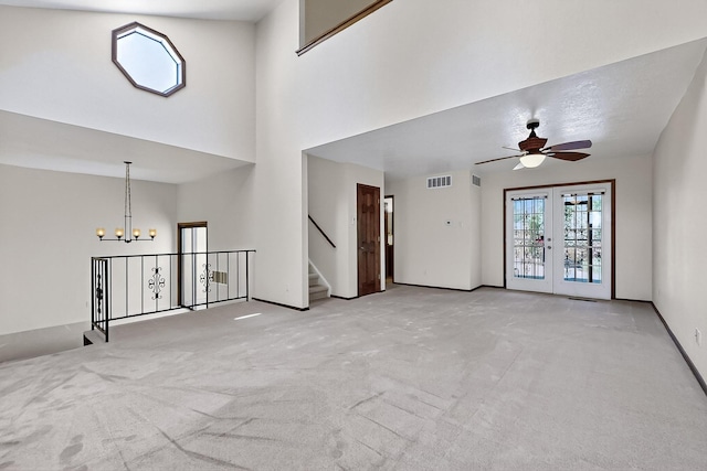 12800 Comanche Rd NE Unit 23, Albuquerque, NM 87111 - unfurnished living room with a chandelier, carpet flooring, ceiling fan, stairway, and french doors