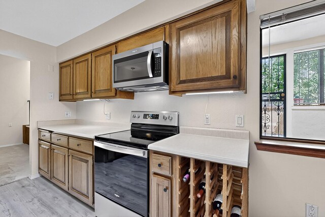 12800 Comanche Rd NE Unit 23, Albuquerque, NM 87111 - kitchen featuring stainless steel appliances, light countertops, brown cabinetry, and light wood-type flooring