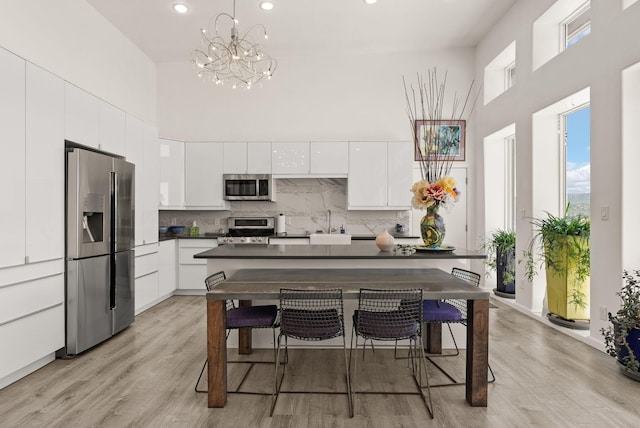 343 Webb Ranch Rd, Pie Town, NM 87827 - kitchen featuring appliances with stainless steel finishes, a towering ceiling, dark countertops, a chandelier, and white cabinetry