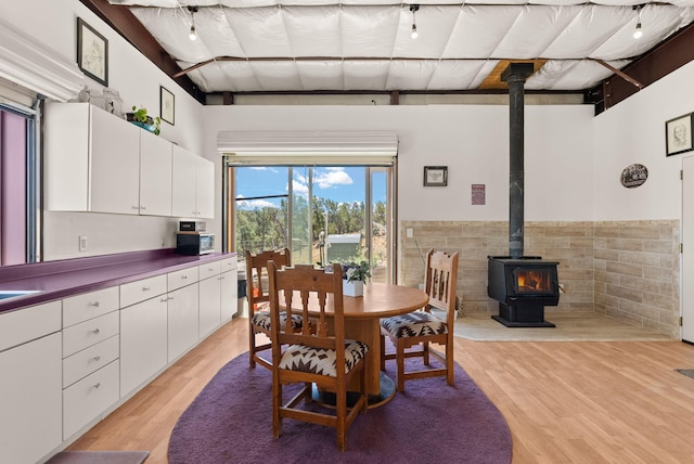 343 Webb Ranch Rd, Pie Town, NM 87827 - dining space with a wood stove, light wood-style flooring, a wainscoted wall, and tile walls