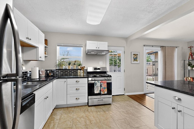8206 Morrow Ave NE, Albuquerque, NM 87110 - kitchen featuring appliances with stainless steel finishes, under cabinet range hood, a textured ceiling, white cabinets, and dark countertops