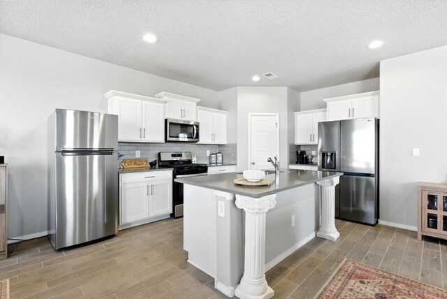 3209 Tazanita Loop SE, Rio Rancho, NM 87124 - kitchen with appliances with stainless steel finishes, light wood finished floors, decorative backsplash, white cabinets, and recessed lighting