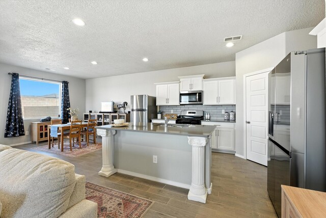 3209 Tazanita Loop SE, Rio Rancho, NM 87124 - kitchen featuring appliances with stainless steel finishes, a textured ceiling, backsplash, open floor plan, and dark wood finished floors