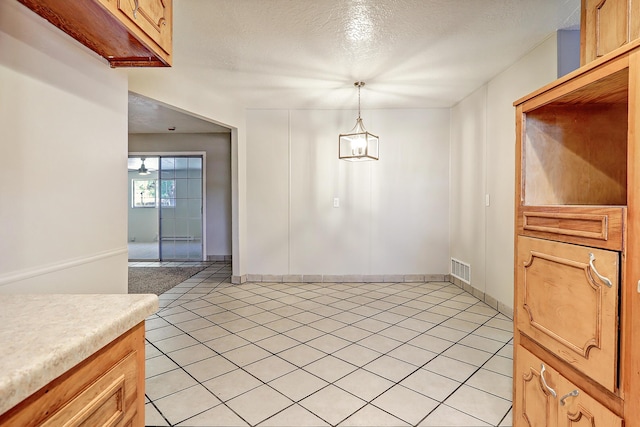 5711 Bohemio Ct SW, Albuquerque, NM 87105 - unfurnished dining area featuring light tile patterned floors, a textured ceiling, and a chandelier