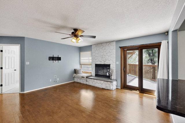 8 Fawn Rd, Cedar Crest, NM 87008 - unfurnished living room featuring a ceiling fan, wood finished floors, a textured ceiling, and a stone fireplace
