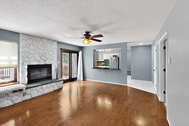8 Fawn Rd, Cedar Crest, NM 87008 - unfurnished living room with ceiling fan, wood finished floors, a textured ceiling, and a stone fireplace