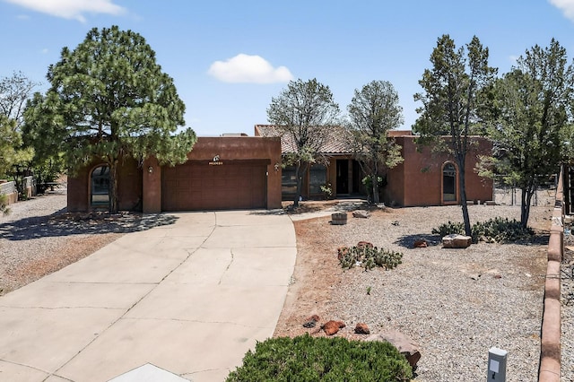 4904 Alberta Ln NW, Albuquerque, NM 87120 - pueblo revival-style home with a garage, concrete driveway, stucco siding, and a tiled roof
