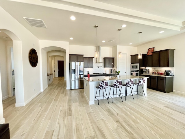 3237 Fennel Rd NE, Rio Rancho, NM 87144 - kitchen with appliances with stainless steel finishes, a breakfast bar area, exhaust hood, light wood finished floors, and tasteful backsplash