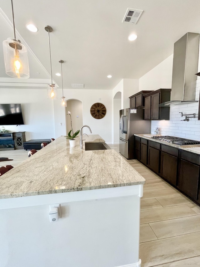 3237 Fennel Rd NE, Rio Rancho, NM 87144 - kitchen with arched walkways, stainless steel appliances, dark brown cabinetry, tasteful backsplash, and light stone countertops