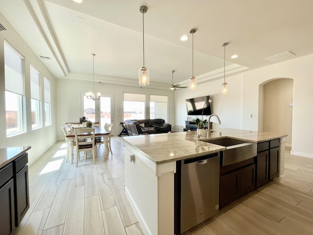 3237 Fennel Rd NE, Rio Rancho, NM 87144 - kitchen featuring stainless steel dishwasher, a tray ceiling, arched walkways, light wood finished floors, and an island with sink
