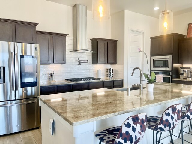 3237 Fennel Rd NE, Rio Rancho, NM 87144 - kitchen featuring appliances with stainless steel finishes, wall chimney exhaust hood, dark brown cabinets, light stone counters, and backsplash