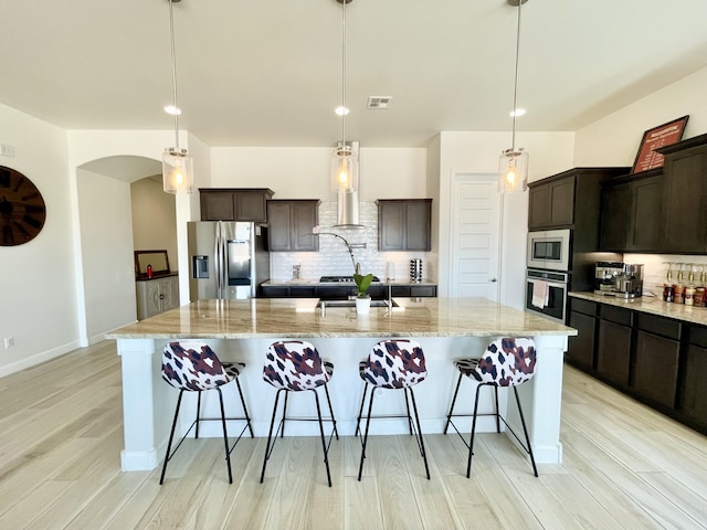 3237 Fennel Rd NE, Rio Rancho, NM 87144 - kitchen with stainless steel appliances, tasteful backsplash, a large island with sink, and light wood-style flooring